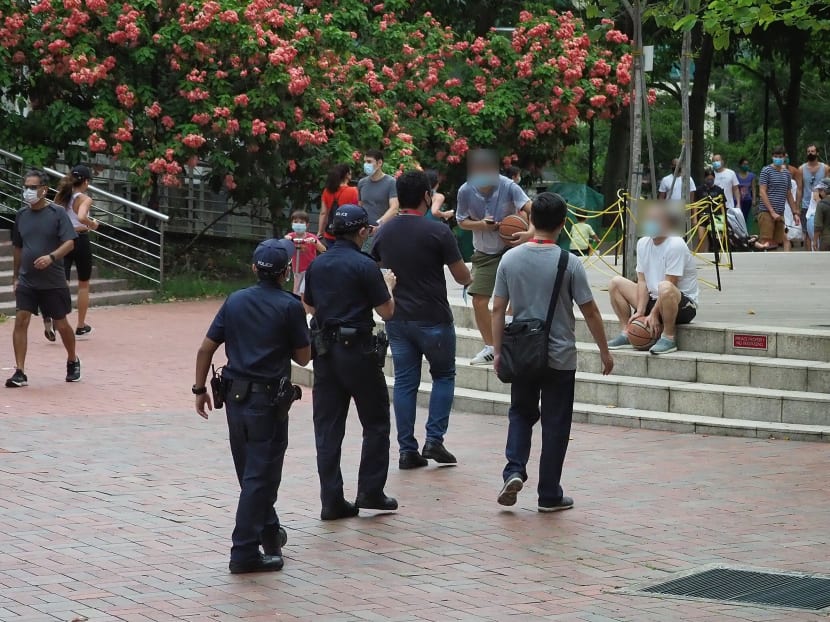Police and enforcement officers approaching people sitting on steps at Robertson Quay on May 17, 2020.