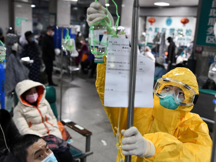 A medical worker in protective suit adjusts a drip bag for a patient at a hospital in Wuhan, Hubei province, China, Feb 3, 2020.