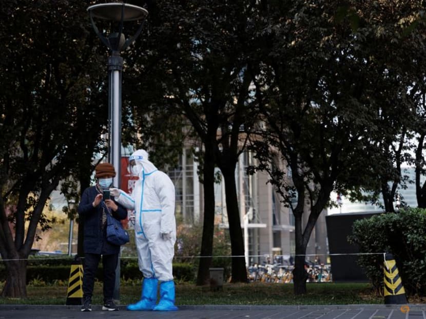 FILE PHOTO: A pandemic prevention worker wears a protective suit as he checks personal details of a woman lining up to get a swab test at a testing booth as outbreaks of coronavirus disease (COVID-19) continue in Beijing, China, November 3, 2022. REUTERS/Thomas Peter FILE PHOTO: A pandemic prevention worker wears a protective suit as he checks personal details of a woman lining up to get a swab test at a testing booth as outbreaks of coronavirus disease (COVID-19) continue in Beijing, China, November 3, 2022. REUTERS/Thomas Peter