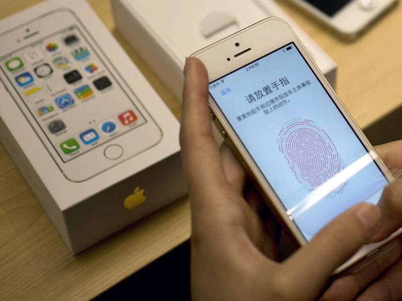 A customer configures the fingerprint scanner technology built into iPhone 5s at an Apple store in Wangfujing shopping district in Beijing on  Sept 20, 2013. Photo: AP