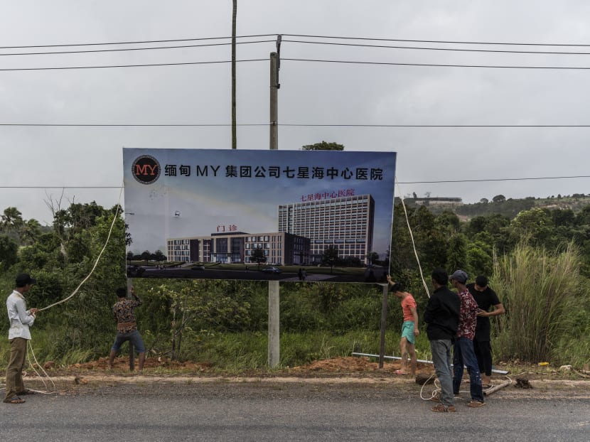 Workers raise a billboard for a construction project in the Dara Sakor investment zone in Cambodia in August 2019.