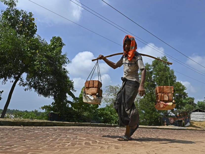 A Rohingya refugee carries bricks at Kutupalong refugee camp in Ukhia. Bangladesh has struggled to support the immense — and immensely traumatised — refugee population, while last year's military coup in Myanmar has made the prospects of a wholesale return even more remote.
