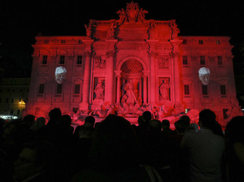 People gather to see the Trevi fountain illuminated red, in memory of Christian Martyrs, in Rome on April 29, 2016.  Photo: ANSA via AP