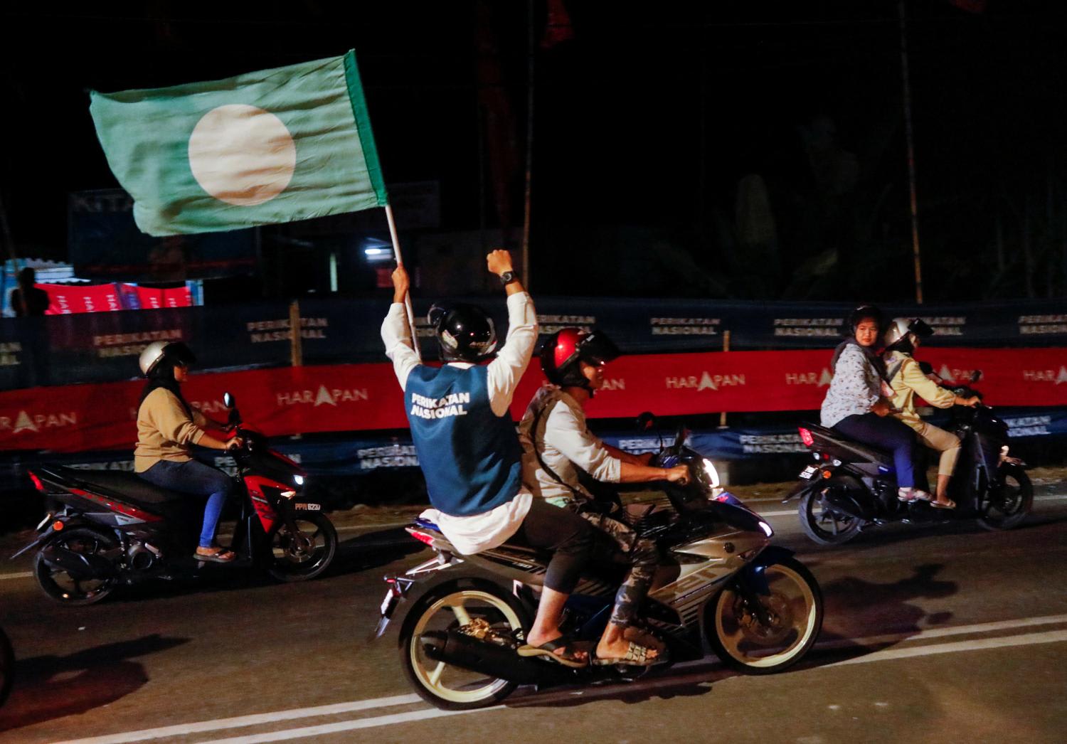 A pillion waves a PAS flag on the eve of Malaysia's general election at Permatang Pauh, Penang, Malaysia on Nov 18, 2022. 