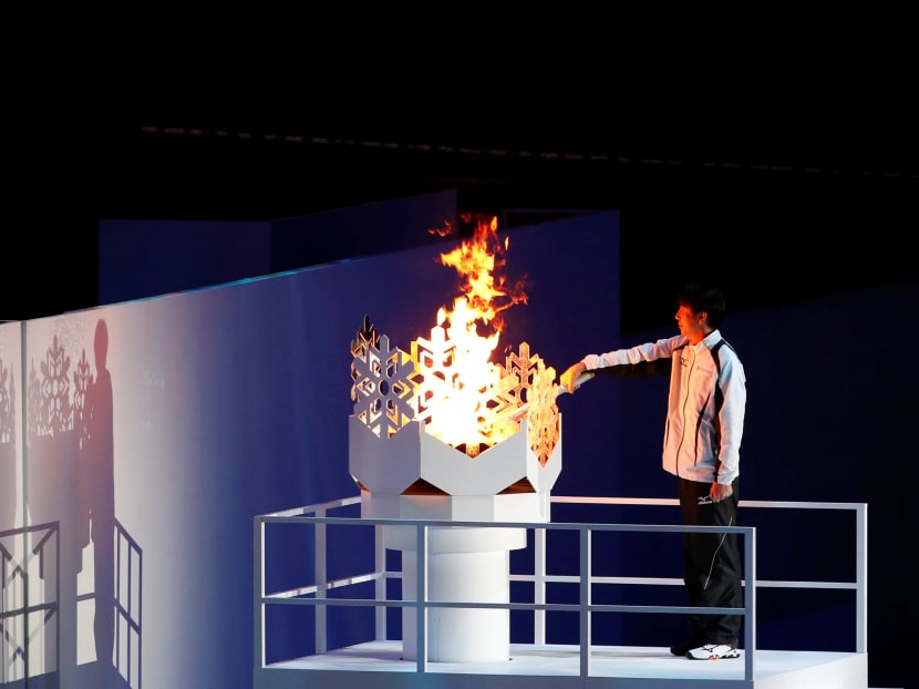 Olympic ski jumping gold medalist Masahiko Harada of Japan holds the torch as he lights the cauldron during the opening ceremony. Photo: REUTERS