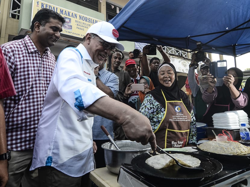 Pakatan Harapan's candidate, Datuk Seri Anwar Ibrahim, tries his hand at making local delicacies during a campaign walkabout at a market in Port Dickson.