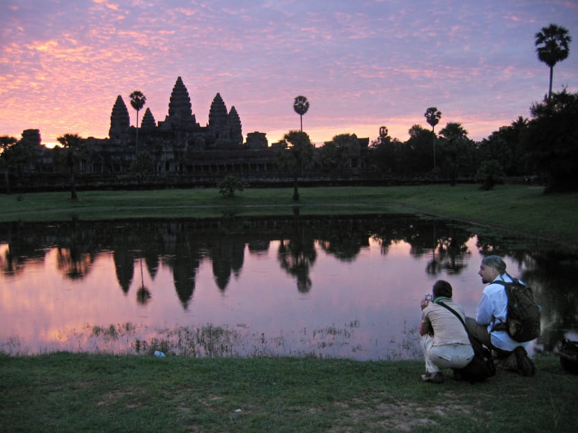 Tourists check out the stunning view of the Angkor Wat temples outside Siem Reap, Cambodia, with the ruins silhouetted by a sunrise, July 14, 2004. Photo: AP