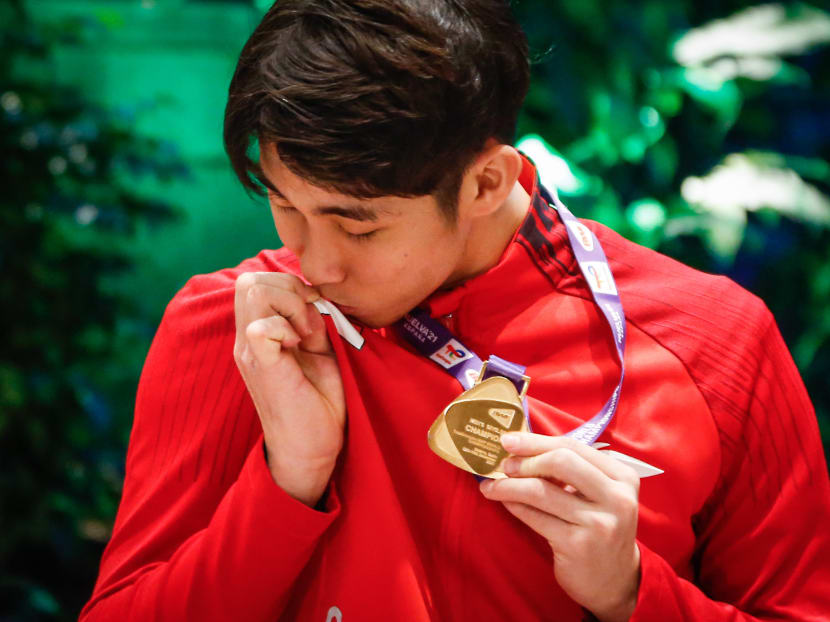 Badminton world champion Loh Kean Yew kissing the Singapore flag on his attire.