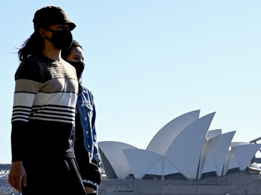 People wearing face masks walk along the Sydney Harbour waterfront with the Opera House in the background amid an extended lockdown due to the Covid-19 pandemic on Aug 13, 2021.