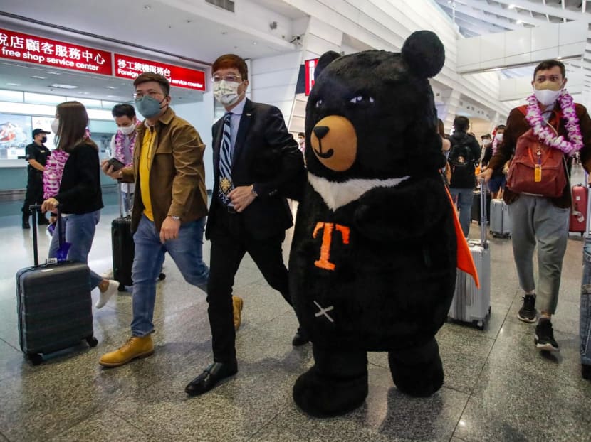 A mascot and an official welcome a group of passengers from Thailand at Taoyuan International Airport in Taoyuan on Oct 13, 2022, after Taiwan reopened its borders by ending mandatory Covid quarantine for arrivals.
