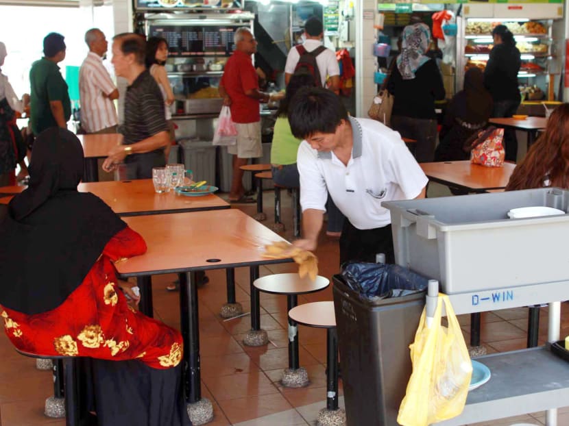 An old man clears tables in a hawker centre at Ang Mo Kio. TODAY file photo
