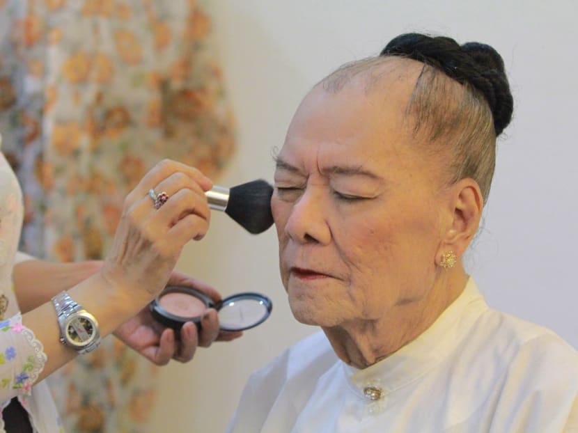 A makeup artist puts the finishing touches to veteran Peranakan female impersonator GT Lye's visage, just before a full-dress rehearsal for Gunong Sayang Association's Kain Chik Dua Mungka (Double-Faced). Photo: Esther Leong/TODAY