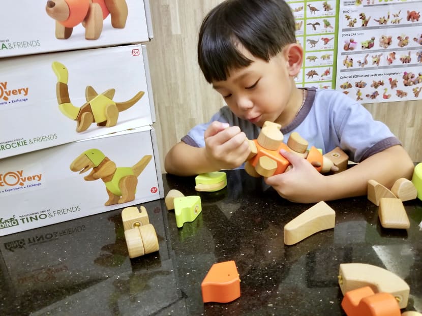Five-year-old Royce Chan playing with a dinosaur model set from new toy-sharing platform Toy Discovery.