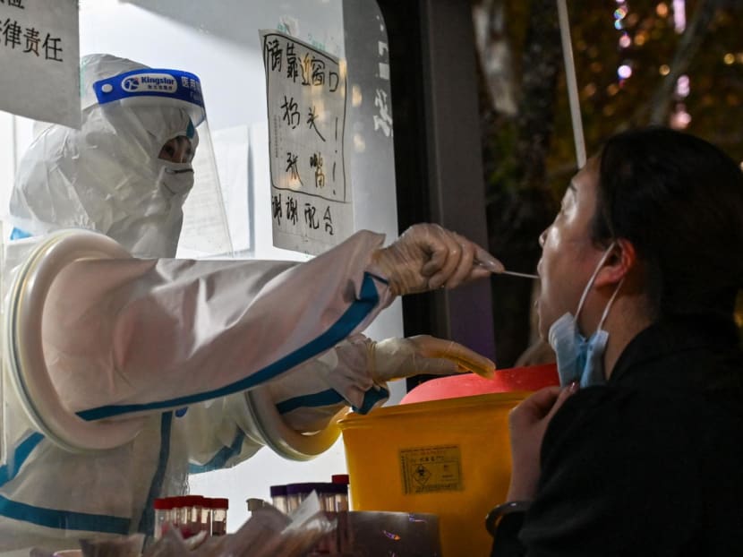A health worker takes a swab sample from a woman to test for Covid-19 in the Jing'an district in Shanghai on Nov 28, 2022.