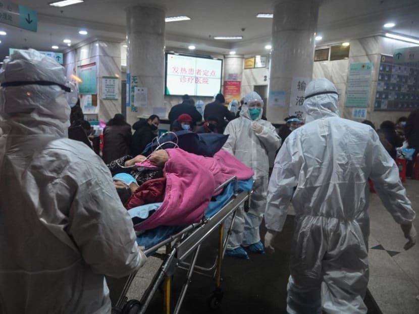 Medical staff wearing protective clothing to protect against a previously unknown coronavirus arrive with a patient at the Wuhan Red Cross Hospital in Wuhan.