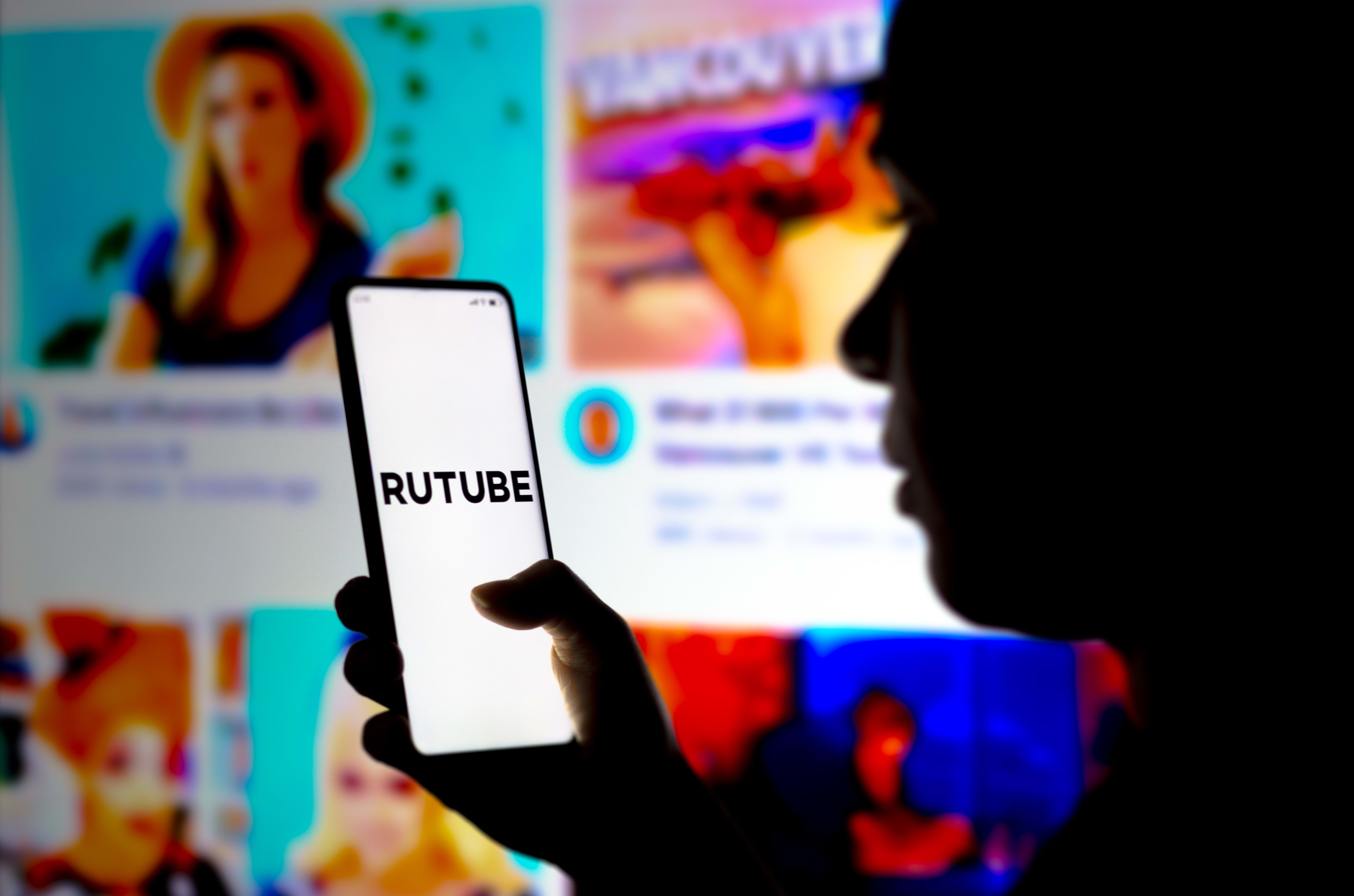 In this photo illustration, a woman's silhouette holds a smartphone with the RuTube logo displayed on the screen. In this photo illustration, a woman's silhouette holds a smartphone with the RuTube logo displayed on the screen.