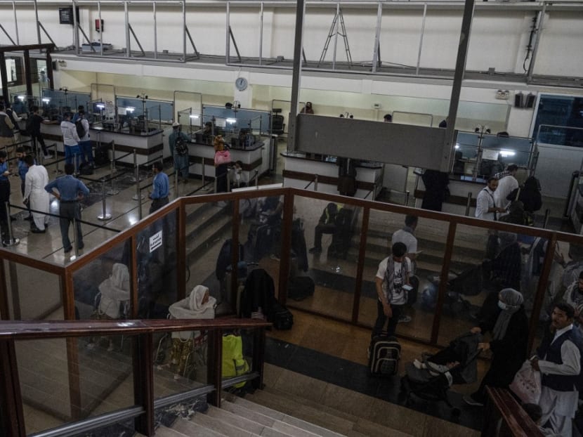 Afghan immigration officers check passport of passengers inside the airport terminal at the Kabul airport in Kabul on Aug 1, 2022.