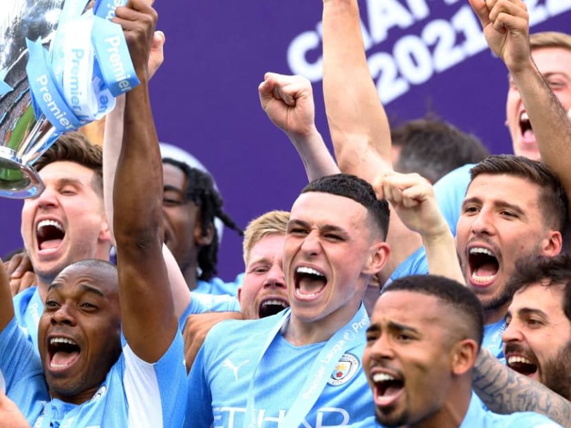 Brazilian footballer Fernandinho from Manchester City football club lifting a trophy as he celebrates with teammates after they won the English Premier League on May 22, 2022.