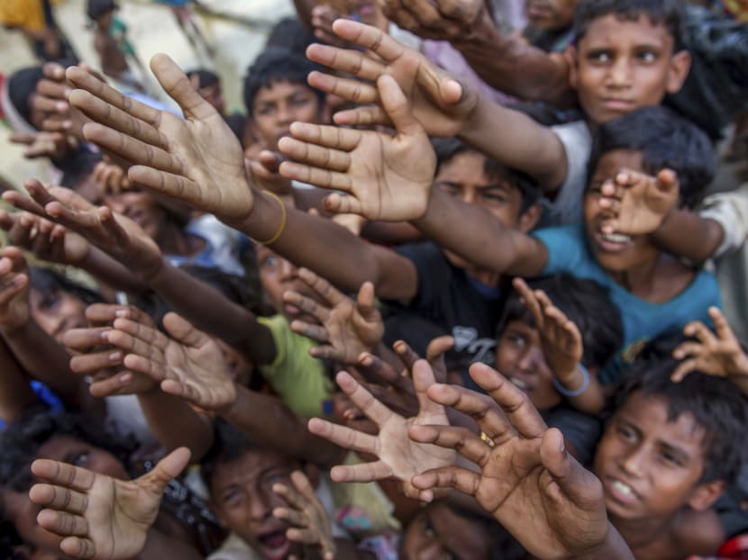 Rohingya Muslim children, who crossed over from Myanmar into Bangladesh, stretch their arms out to collect chocolates and milk distributed by Bangladeshi men at Taiy Khali refugee camp, Bangladesh, Thursday, Sept. 21, 2017. Photo: AP