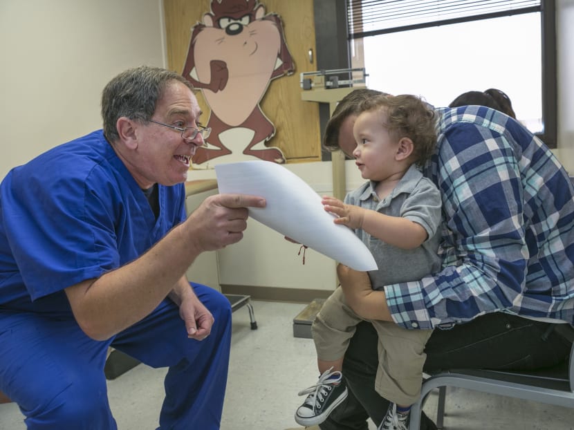 Pediatrician Charles Goodman, left, explains to Frank Fierro, the father of 1 year-old Cameron Fierro, the need of getting the measles-mumps-rubella vaccine, or MMR vaccine at his practice in Northridge, California, Jan 29, 2015. Photo: AP