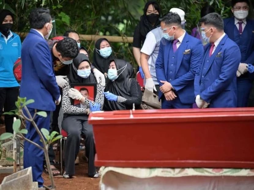 Ms Aldha Refa (seated, centre), the wife of Okky Bisma, a flight attendant and one of the 62 people aboard Sriwijaya Air flight SJ182 which crashed shortly after takeoff on January 9, holds his photo while surrounded by family and friends during his funeral in Jakarta on January 14, 2021.