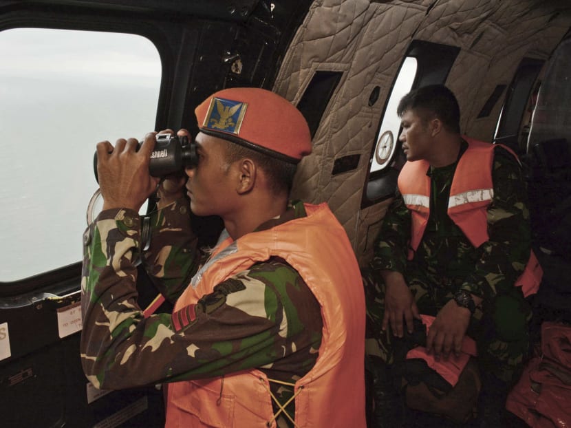 A crewmember of an Indonesian Air Force Super Puma helicopter of 6th Air Squadron uses a binocular to scan the horizon during a search operation for the victims of AirAsia Flight QZ 8501 over the Java Sea January 1, 2015.  REUTERS