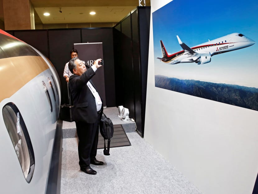 A visitor takes a picture of a poster of Mitsubishi Regional Jet (MRJ) during Japan Aerospace 2016 air show in Tokyo, Japan, October 12, 2016. Reuters file photo