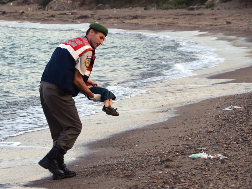 A paramilitary police officer carries the lifeless body of a  migrant child after a number of migrants died and a smaller number  were reported missing after boats carrying them to the Greek island of Kos capsized, near the Turkish resort of Bodrum early Sept. 2, 2015. Photo: AP