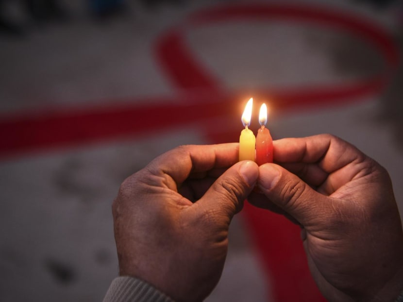 A volunteer lights candles forming the shape of a red ribbon during an awareness event on the eve of World Aids Day, in Kathmandu, Nepal, on Nov 30, 2020.