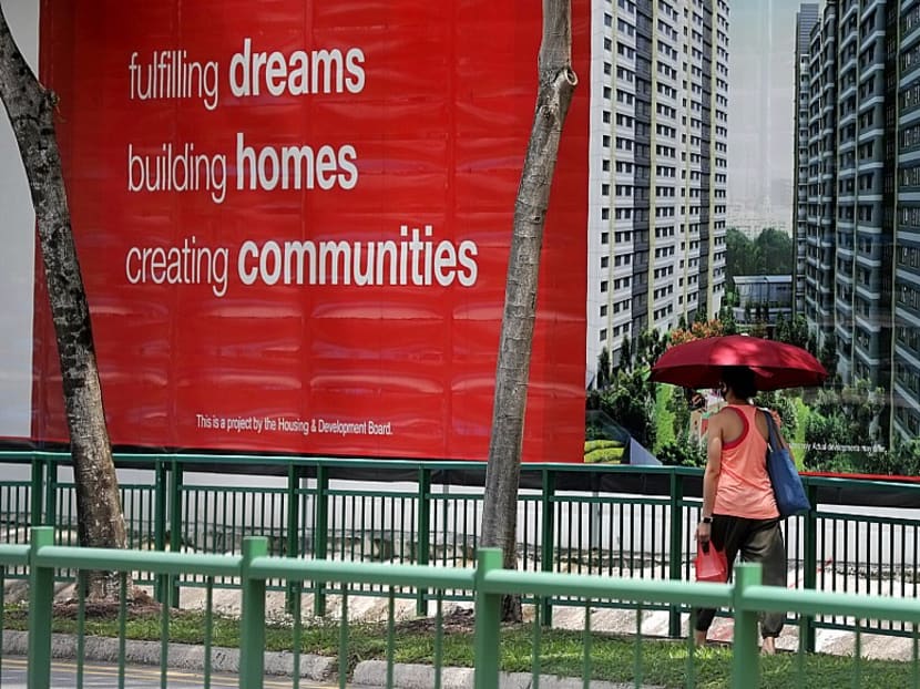 A woman walking by a hoarding at a construction site of a Built-To-Order public housing project. 