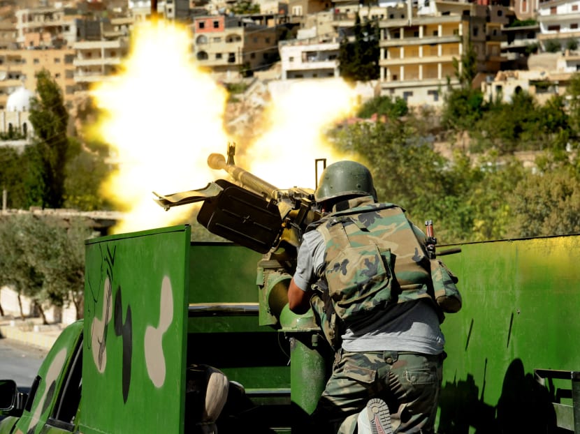 a Syrian military solider fires a heavy machine gun during clashes with rebels. Photo: AP/ Official Syrian news agency SANA