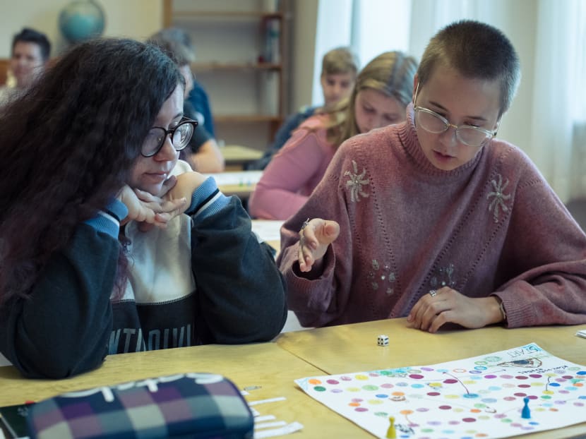 Two 10th grade students play a board game created by one of them.