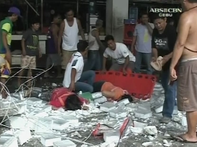 Men tend to women lying on the ground near debris after buildings collapsed during an earthquake in Cebu City, Philippines, in this Oct 15, 2013 still image taken from video. Photo: Reuters/ABS-CBN