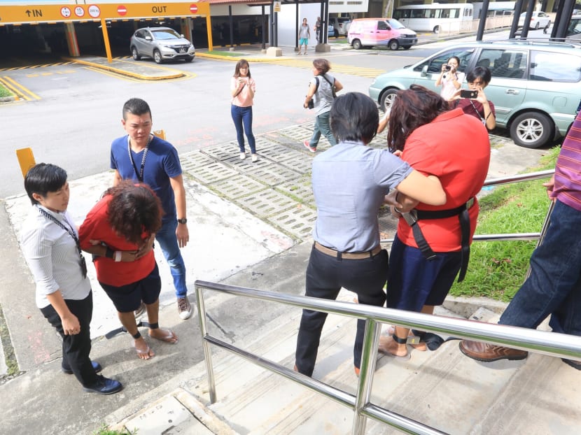 Prema S Naraynasamy (left in red), 58, and her daughter Gaiyathiri Murugayan (right in red), 36, seen crossing path while escorted separately to their Bishan flat for a re-enactment of their crime on 3 August 2016. Photo: Koh Mui Fong