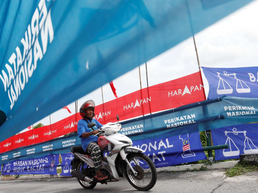 A motorcyclist rides past the party flags and banners during the campaign period of Malaysia's general election in Ipoh, Perak, Malaysia November 6, 2022.