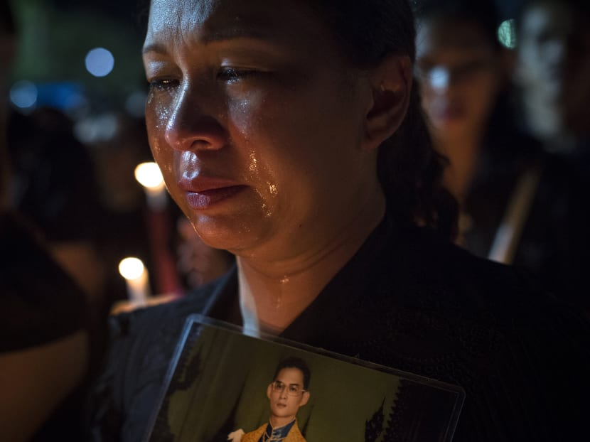 A Thai mourner cries as others clad in black light candles for late Thai King Bhumibol Adulyadej at the Sanam Luang Park outside the Grand Palace in Bangkok on Oct 22, 2016. Photo: AFP
