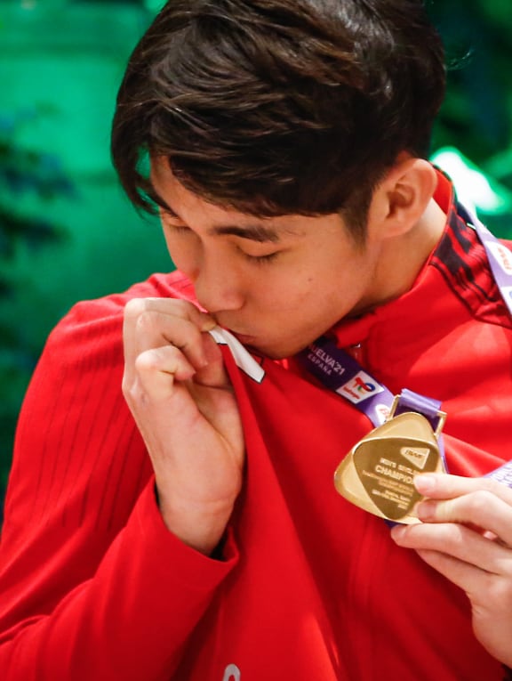 Badminton world champion Loh Kean Yew kissing the Singapore flag on his attire.