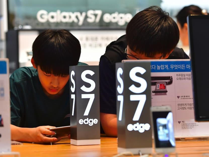 Visitors test Samsung Electronics' Galaxy S7 edge at its showroom in Seoul on July 7, 2016. Photo: AFP