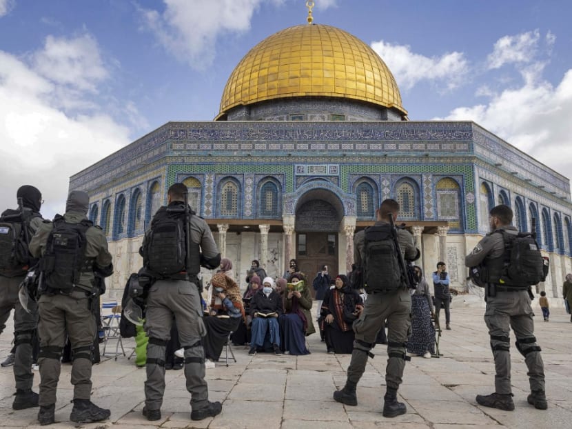 Israeli policemen stand guard in front of Muslim women praying in front of the Al-Aqsa mosque in Jerusalem on April 20, 2022. 
