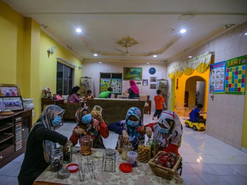 Family members prepare jars of cookies at home in Kampung Changkat, Gombak on the eve of Hari Raya Aidilfitri, May 23, 2020.