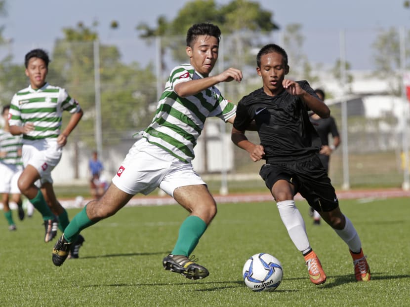 An SJI player (green & white) challenges for the ball against a Hong Kah Secondary School (black) player. Photo: Wee Teck Hian/TODAY