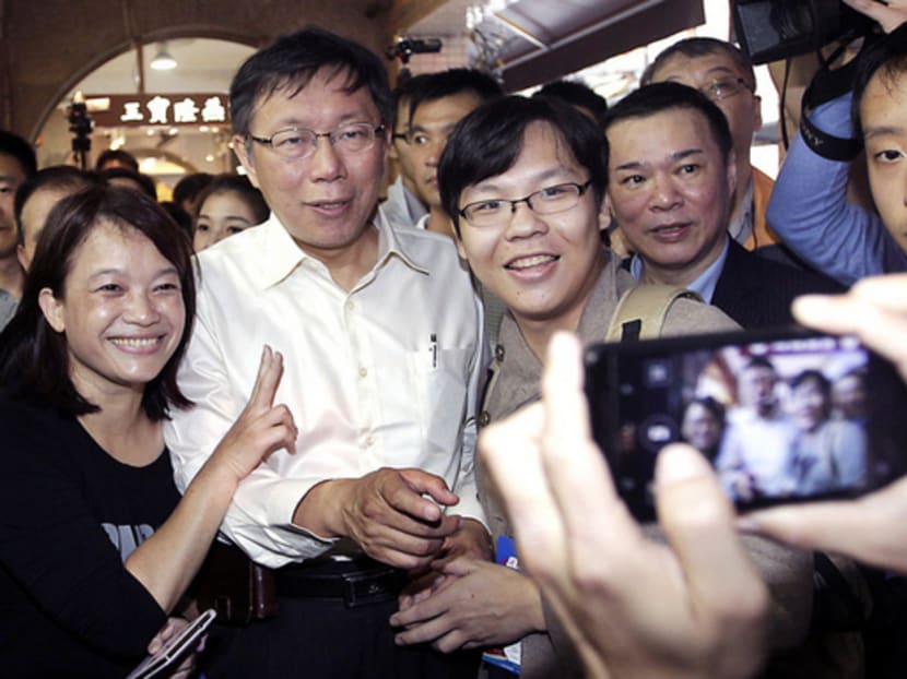 Taipei mayoral candidate Ko Wen-je (second from left) posing for pictures with supporters during an electoral campaign visit to a market ahead of local elections in Taipei on Nov 28, 2014. Photo: Reuters