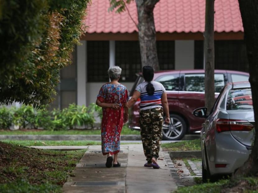 A foreign domestic worker is seen strolling with an elderly woman.