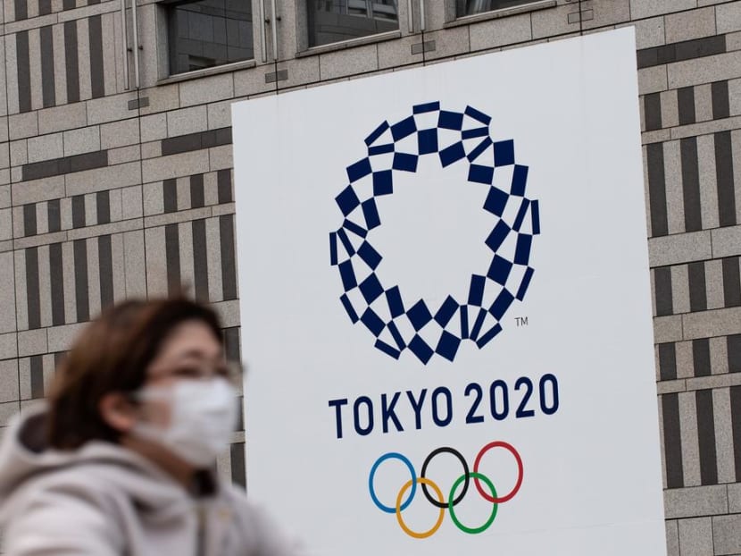 A woman wearing a face mask rides her bike in front of the Tokyo 2020 Olympic games logo outside the Tokyo Metropolitan Government Building on April 23, 2020. A woman wearing a face mask rides her bike in front of the Tokyo 2020 Olympic games logo outside the Tokyo Metropolitan Government Building on April 23, 2020.