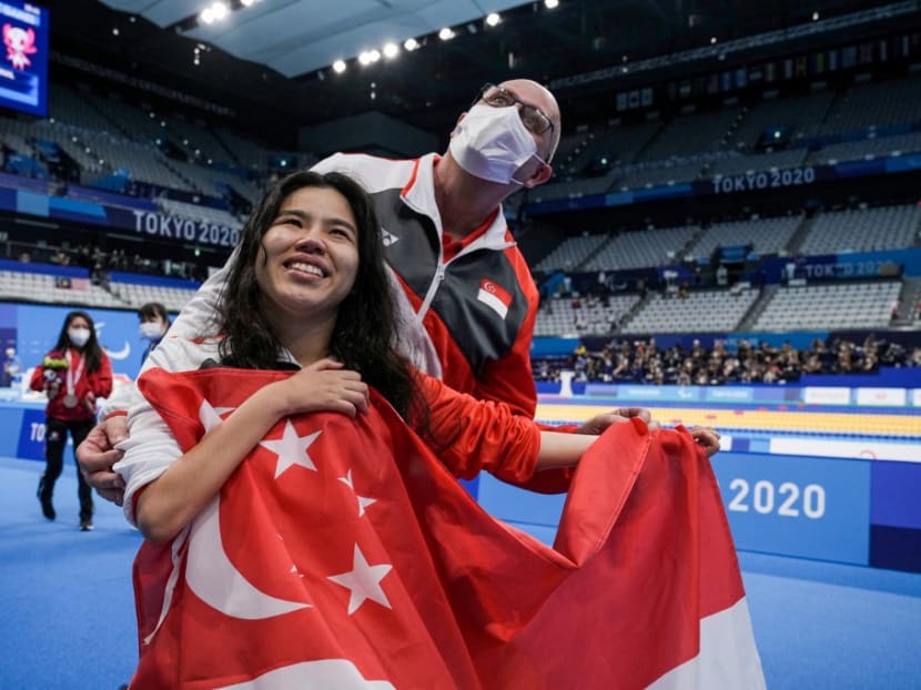 Gold medallist Singapore's Yip Pin Xiu celebrates with a national flag after the women's 100m backstroke swimming event during the Tokyo 2020 Paralympic Games at the Tokyo Aquatics Centre in Tokyo on Aug 25, 2021.