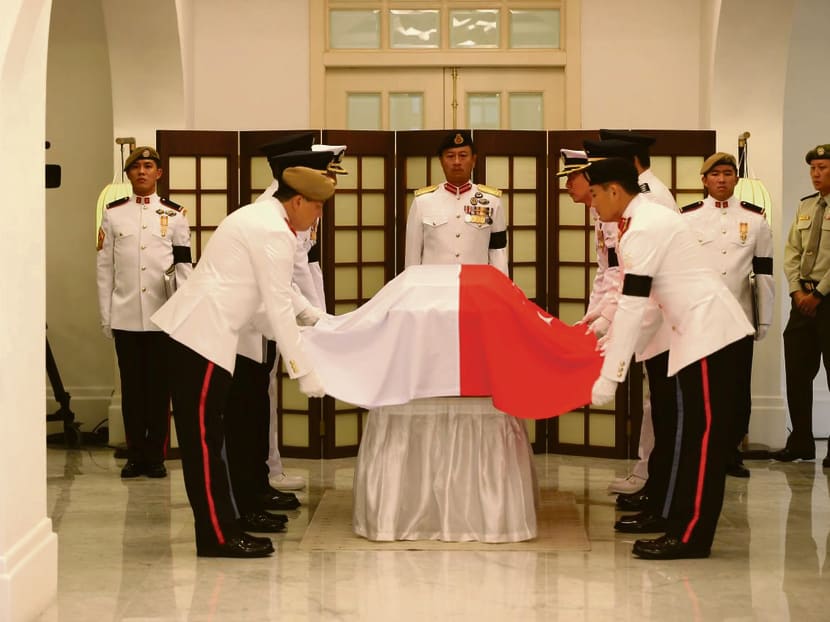 The Guard of Honour draping the national flag over Mr Lee’s coffin in the Istana before the procession left for Parliament House, where the public could pay their last respects. Photo: Reuters
