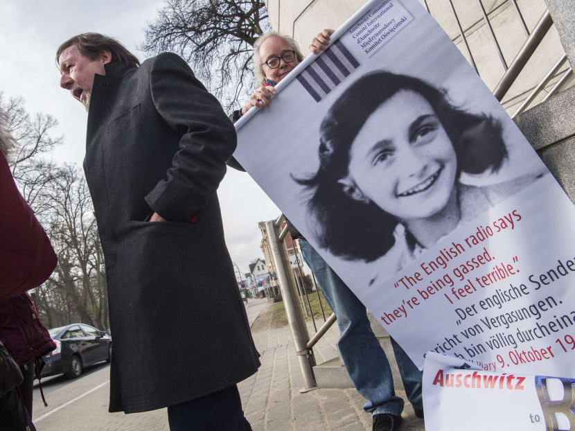 An activist with the Inernational Auschwitz Committee rolls up a poster featuring Holocaust victim Anne Frank outside the regional court of Neubrandenburg during the first day of the trial against former SS medic Hubert Zafke, accused of aiding in 3,681 murders in Auschwitz in 1944, on Feb 29, 2016. Photo: AFP