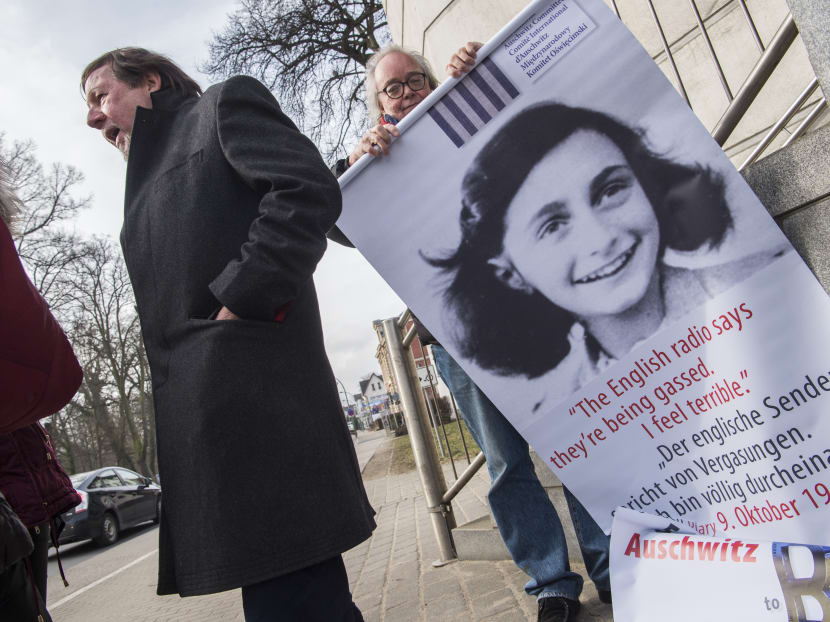 An activist with the Inernational Auschwitz Committee rolls up a poster featuring Holocaust victim Anne Frank outside the regional court of Neubrandenburg during the first day of the trial against former SS medic Hubert Zafke, accused of aiding in 3,681 murders in Auschwitz in 1944, on Feb 29, 2016. Photo: AFP An activist with the Inernational Auschwitz Committee rolls up a poster featuring Holocaust victim Anne Frank outside the regional court of Neubrandenburg during the first day of the trial against former SS medic Hubert Zafke, accused of aiding in 3,681 murders in Auschwitz in 1944, on Feb 29, 2016. Photo: AFP