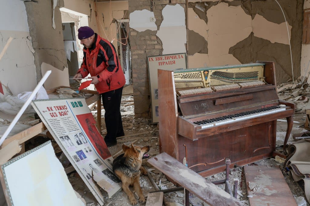 A man collects pictures from a school hit by Russian rockets in the southern Ukraine village of Zelenyi Hai on April 1, 2022. 