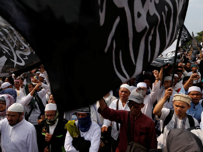 A group of protesters holds a Hizbut Tahrir Indonesia flag during a protest against the President Joko Widodo's decree to disband Islamist groups in Jakarta.